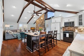 A spacious kitchen with a stone accent wall, wooden beams, and a large island with bar stools.