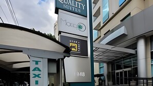 Ein Hotel Eingang mit einem Schild für 'Quality Suites' und einem Taxistand mit der Nummer 308.