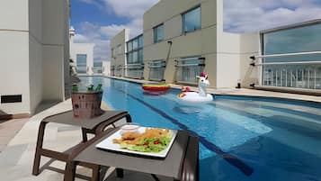 Een buitenzwembad, parasols bij het zwembad en ligstoelen