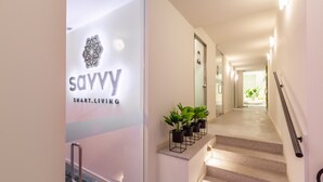 A modern hotel entrance with a glass door displaying the logo and name 'savvy smart living'. A staircase with a handrail and potted plants is visible. - eng (Oporto)