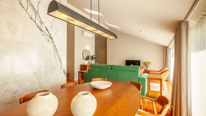 A modern dining area with a wooden table, two white vases, and a green sofa in the background. - eng (Oporto)