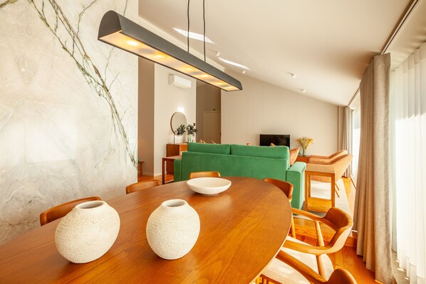 A modern dining area with a wooden table, two white vases, and a green sofa in the background. - eng (Oporto)