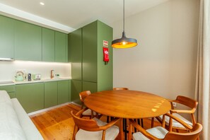A modern kitchen with green cabinets, a wooden dining table, and chairs. - ing (Oporto)
