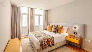 Un dormitorio moderno con una cama grande, una mesita de noche con lámpara y un banco.