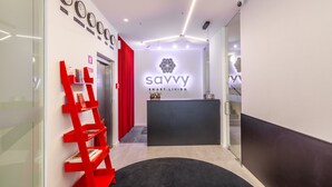 A reception area with a modern design, featuring a black reception desk, a logo on the wall, and a red bookshelf. - ing (Oporto)