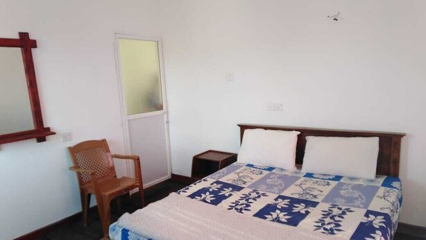 Une chambre à coucher avec un lit, une chaise, une table de chevet et un miroir au mur.