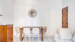 A dining area with a wooden table, four chairs, a wooden cabinet, and a wall-mounted mirror. - Almada Saudade by Hopstays | Mezzanine & Charm (Almada)