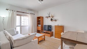 A modern living room with a sofa, coffee table, TV stand, and wooden cabinets. - Almada Saudade by Hopstays | Mezzanine & Charm (Almada)