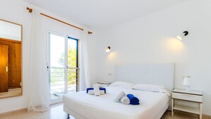A hotel room with a large bed, a nightstand, a mirror, and a sliding glass door to the outside. - Cala Mendia Beach House 2 es with direct access to the beach and sea views (Portocristo - Cala Mandia)