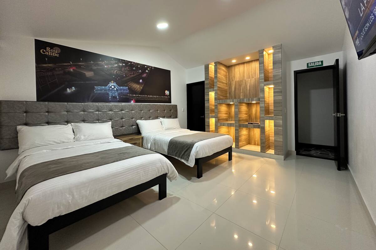 Une chambre d’hôtel avec deux lits, une grande affiche au mur et un mur décoratif en bois doté d’un éclairage intégré.