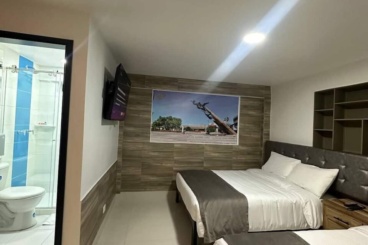Une chambre d’hôtel moderne dotée d’une grande fenêtre, d’un espace douche, d’un lit avec une tête de lit et d’un téléviseur fixé au mur.