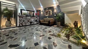 Un hall d’hôtel au design moderne, comprenant un comptoir d’accueil, un canapé et un escalier.