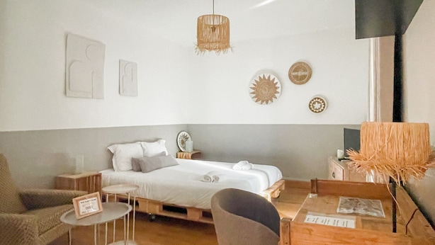 A minimalist bedroom with a bed, bedside table, chair, and a small round table. - Bamboo Caban 2 min du centre ville (Annecy)