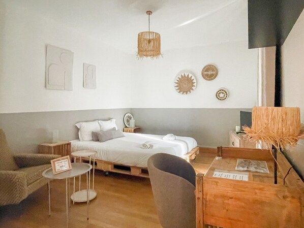 A minimalist bedroom with a bed, bedside table, chair, and a small round table.