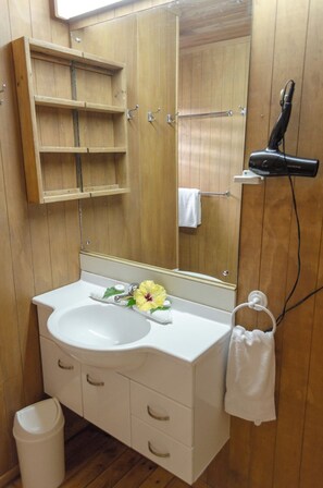 A bathroom with a wooden vanity, a sink, a mirror, a towel rack, and a hairdryer. - Koromiri Bungalow (Rarotonga)