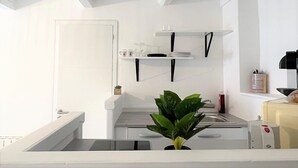 Una cocina moderna con armarios blancos, una encimera negra y una planta en el centro.