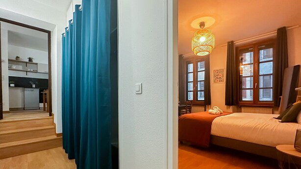 Ein Zimmer mit einem Bett, einem Schreibtisch, einem Stuhl, einer Lampe und einem Fenster.