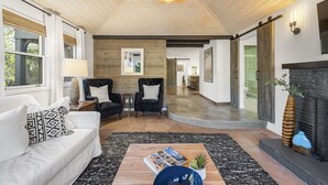 Un salon moderne avec un canapé, des fauteuils, une table basse et une cheminée.