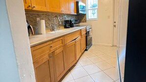 A kitchen with wooden cabinets, a stainless steel sink, and a black refrigerator.