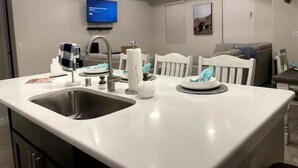 A modern kitchen with a large island, built-in appliances, and a flat-screen TV mounted on the wall. - Las Cruces, New 4BR home, Vacation, Games, Pickleball, Family Friendly (Las Cruces)