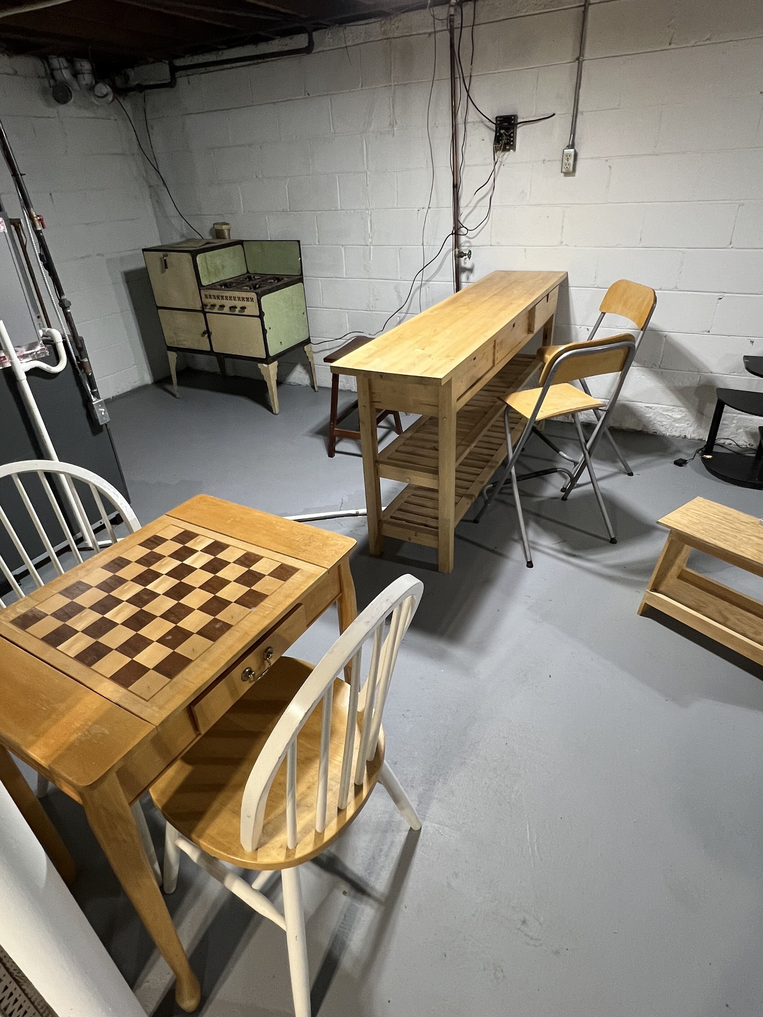 Une pièce avec une table et des chaises en bois, un jeu d’échecs et un buffet vert.
