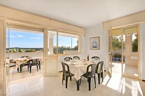 Un comedor con una mesa dispuesta para seis personas, ventanas amplias y vistas al exterior.