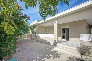 A building with a paved walkway, a covered entrance, and a door leading inside.
