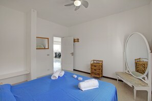 Une chambre à coucher comprenant un lit, un miroir, un banc et une porte donnant sur un balcon.
