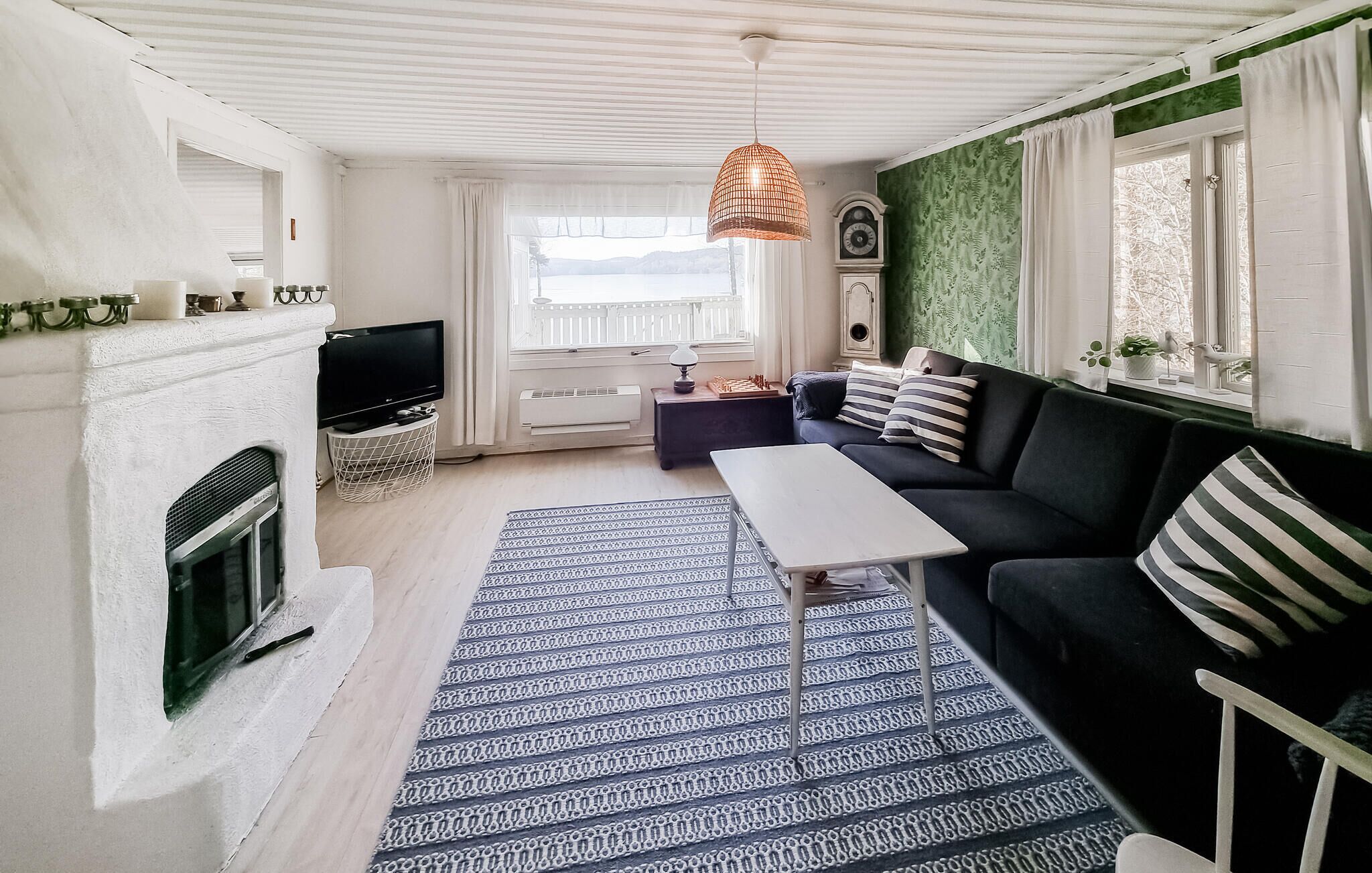 Un salon avec une cheminée, un canapé, un téléviseur et un tapis à motifs.