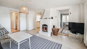 Un salón amplio con chimenea, televisor y mesa de comedor.