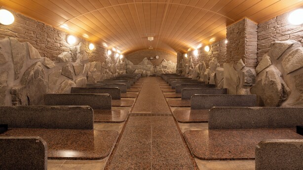 Eine Sauna mit Steinwänden und in Reihen angeordneten Bänken.