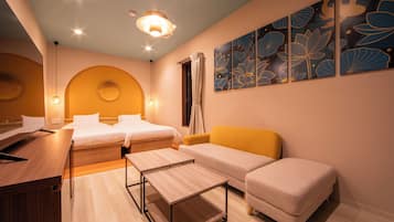 A hotel room with two beds, a sofa, a desk, and a large floral artwork on the wall.