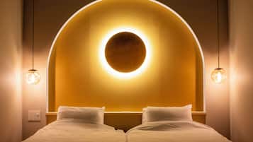 A hotel room with a bed, a circular light fixture above the headboard, and two pendant lights.