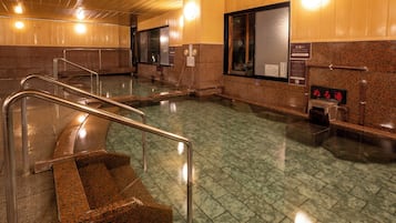 A public bath area with a staircase, metal handrails, and a tiled floor.