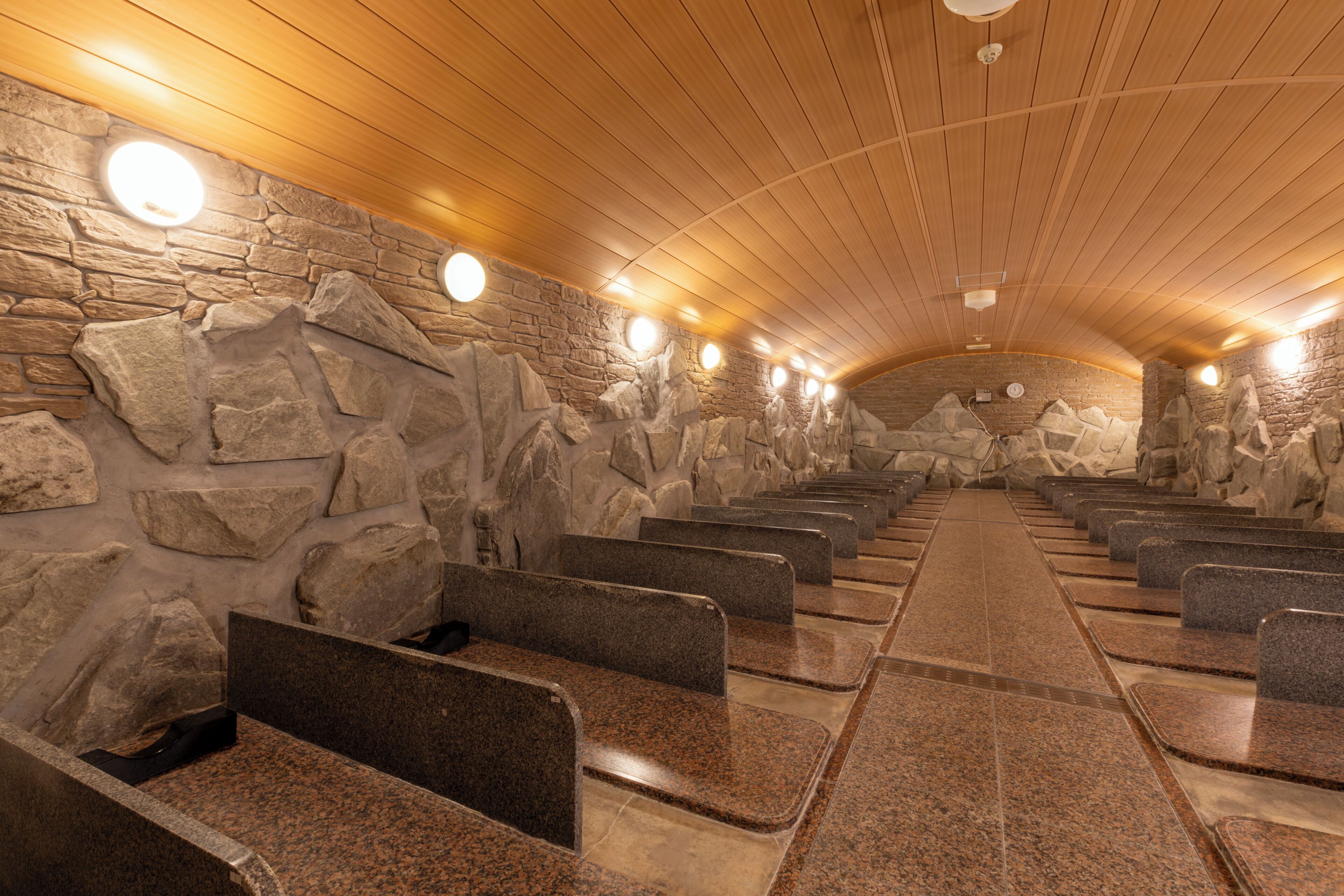Un sauna aux murs en pierre et aux bancs en bois.