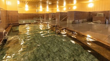 A swimming pool with clear water, surrounded by stone walls and metal railings.