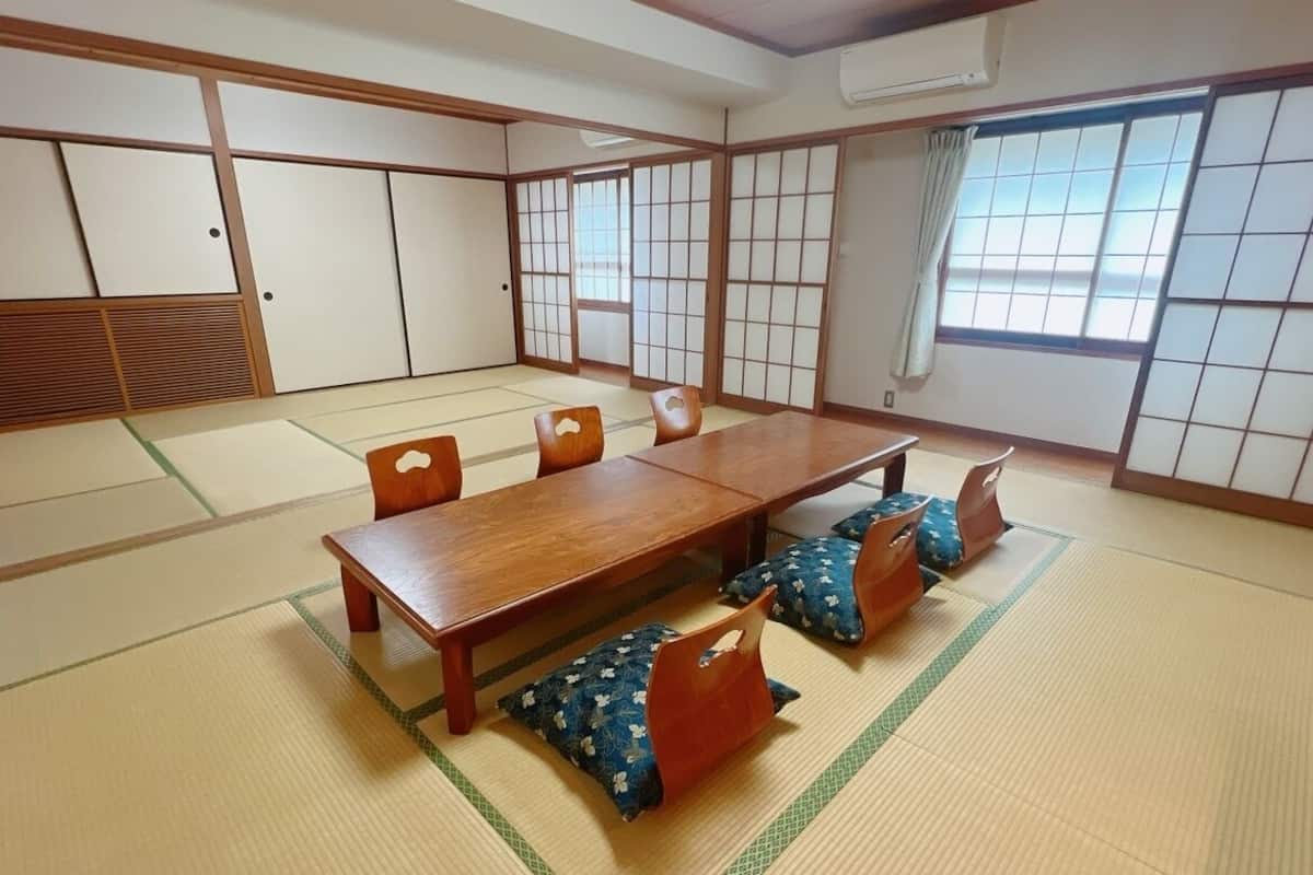 Ein traditioneller japanischer Raum mit Tatami-Bodenbelag, einem Holztisch und Shoji-Schirmwänden.