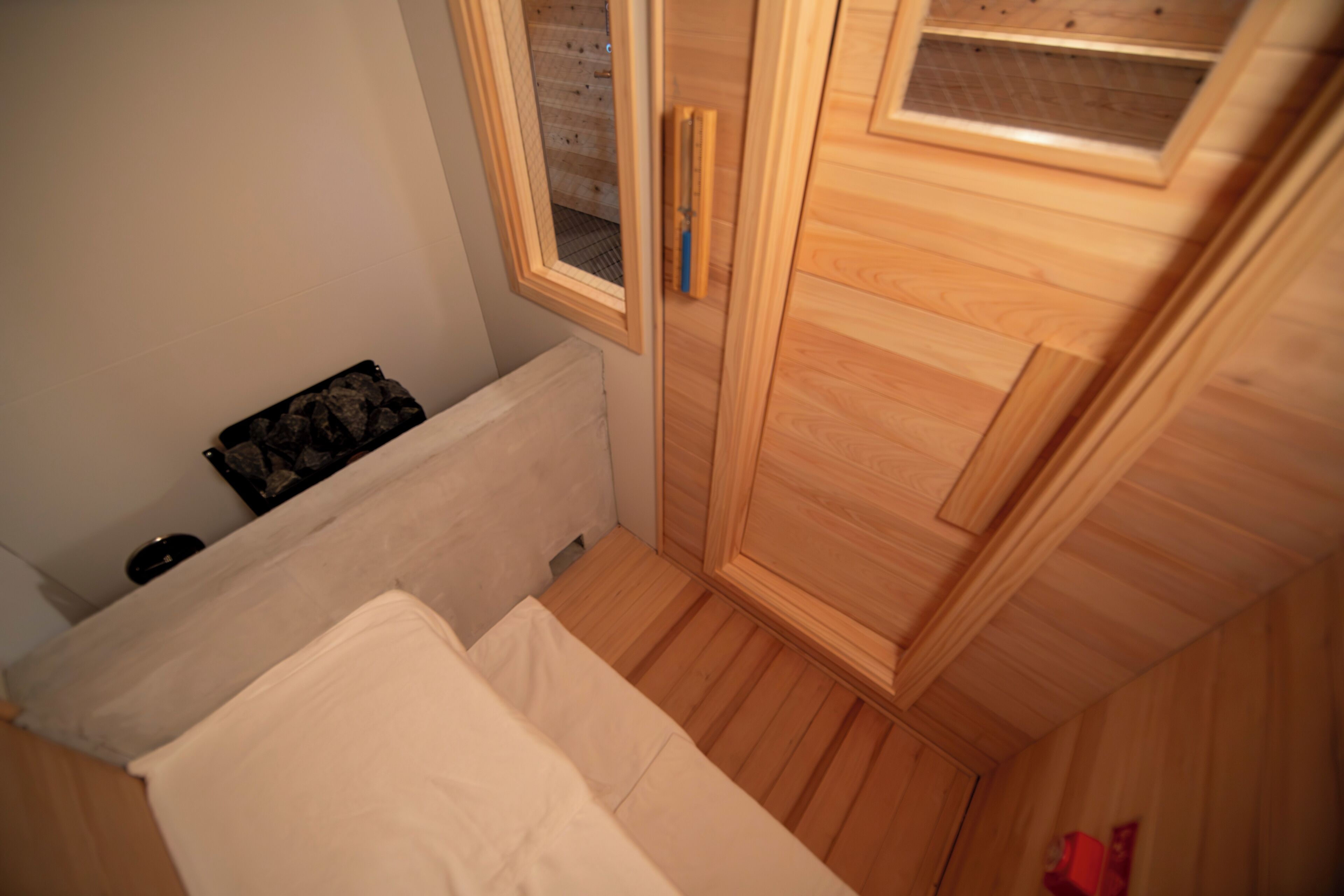 A bedroom with a wooden wardrobe, a radiator, and a window with a view of the outside.