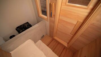 A bedroom with a wooden wardrobe, a radiator, and a window with a view of the outside.