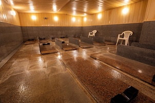 A sauna room with benches and chairs, wooden walls, and a tiled floor.