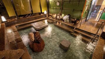 Un onsen japonés tradicional con baños de piedra y estructura de madera.