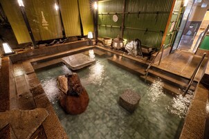 Un onsen japonais traditionnel, avec des bains en pierre et une structure en bois.