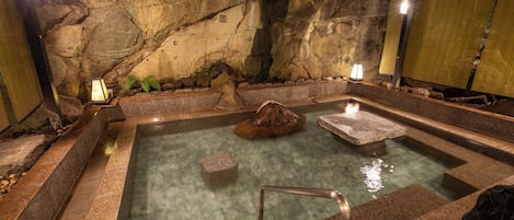 A hot spring bath with stone walls and a wooden bench.