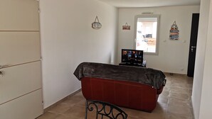 Ein Schlafzimmer mit Bett, Fernseher, Kleiderschrank und einem Fenster mit Jalousien.
