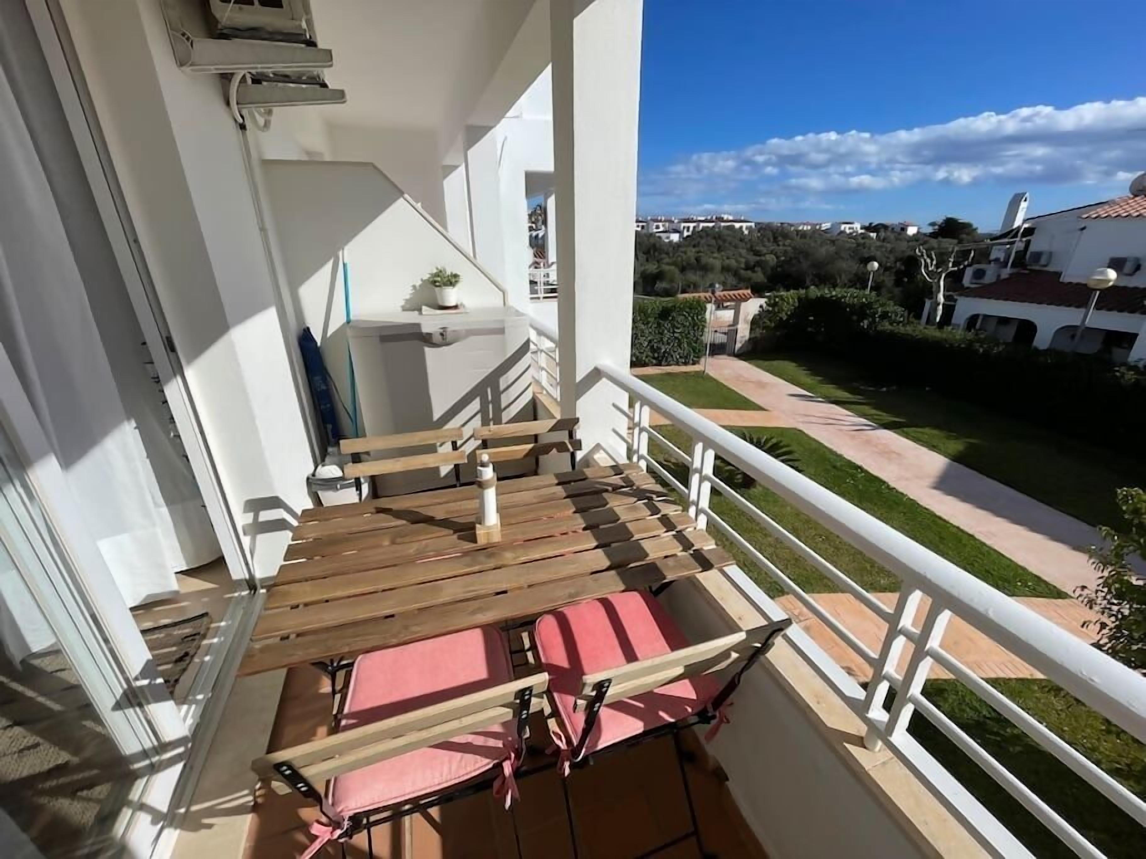 A balcony with a wooden floor, a white railing, and a view of a residential area.