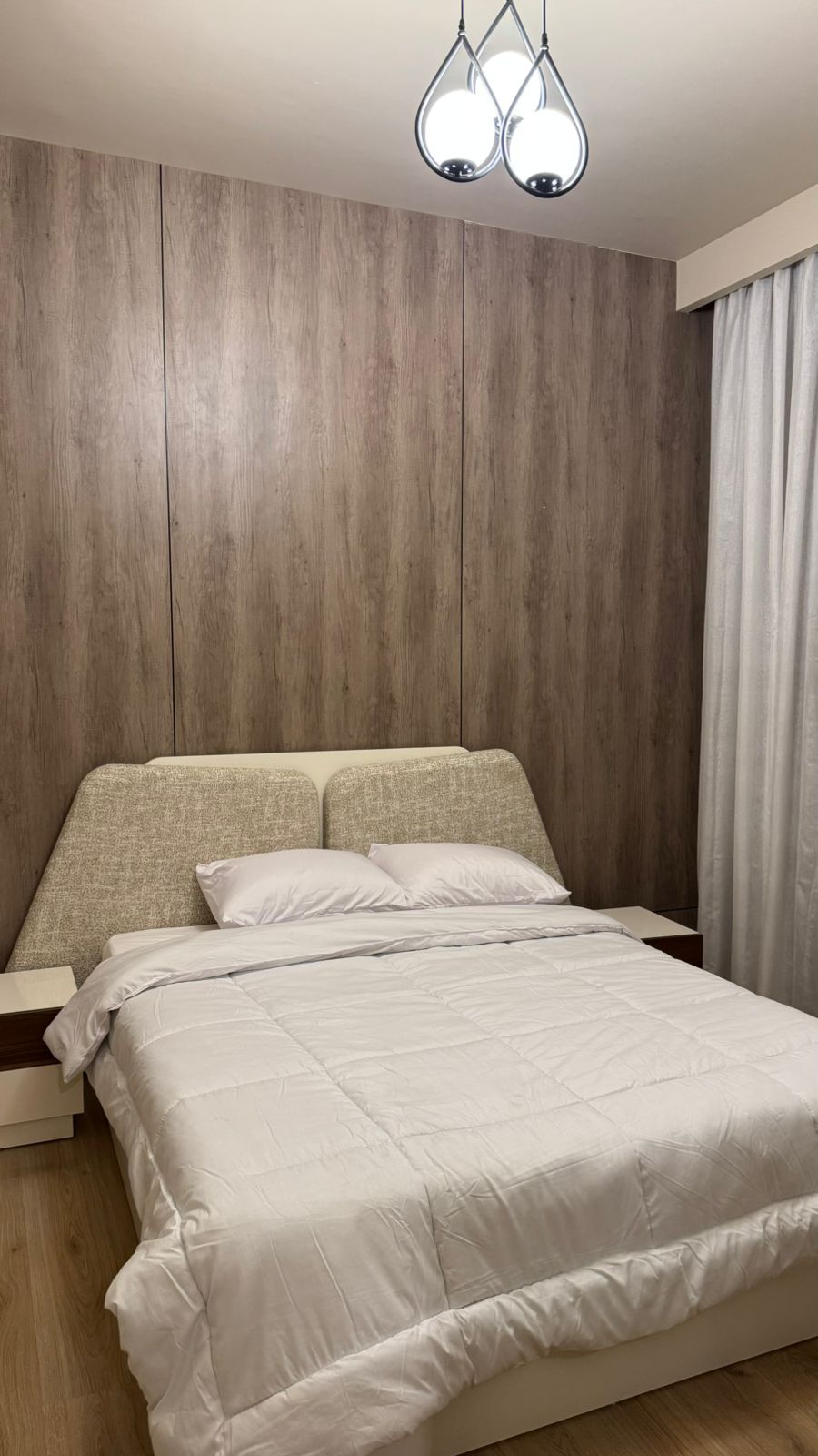 Une chambre à coucher avec une tête de lit en bois, un lit avec une literie blanche et une table de chevet.