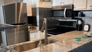 A modern kitchen with stainless steel appliances, granite countertops, and white cabinetry. - Beachfront condo with amazing views of the sunset, family friendly, and safe. (Panama City Beach)