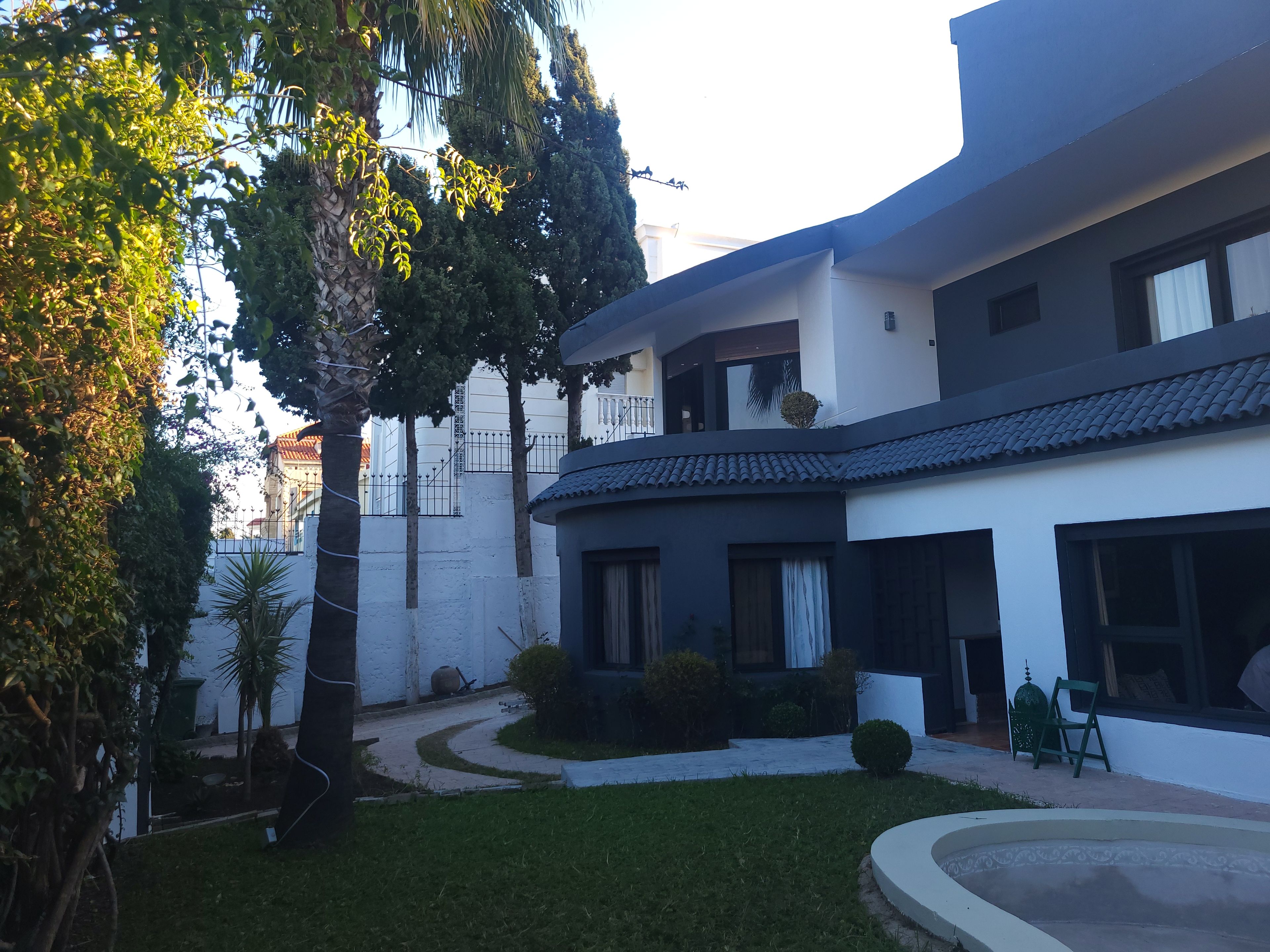 A modern two-story building with a white facade and dark roof tiles.
