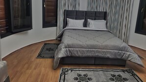 A bedroom with a large bed, a headboard, and two windows with blinds. - Villa Adam Tangier (Tangier)