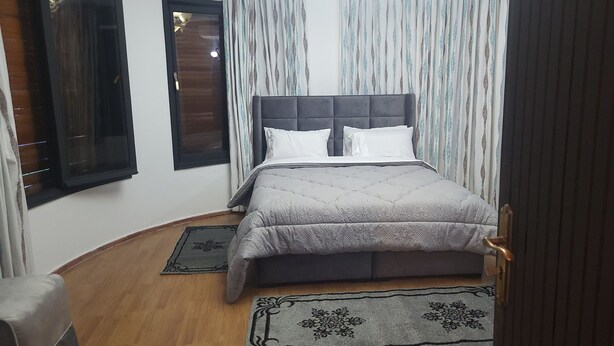 A bedroom with a bed, two windows, a door, and a chair. - Villa Adam Tangier (Tangier)